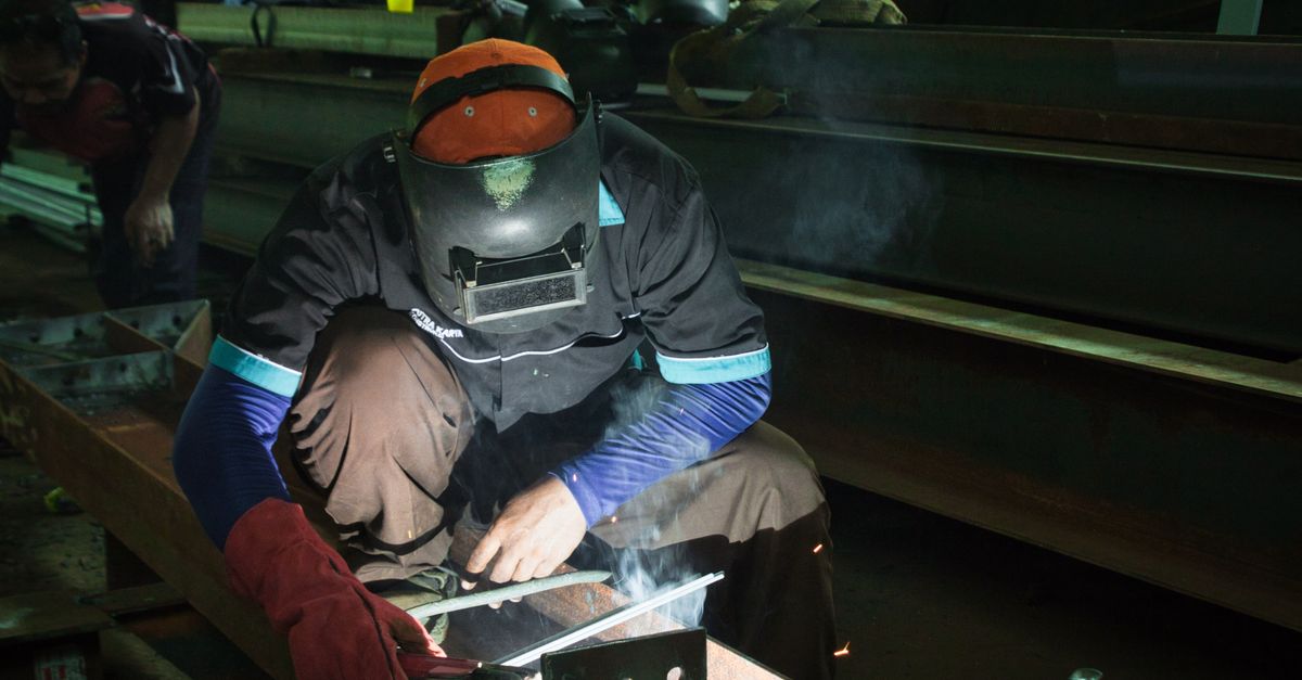 Gambaran bengkel las dengan pekerja mengelas rangka besi